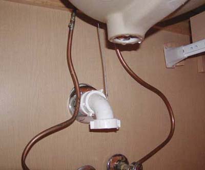 Bathroom sink missing drain pipe and P-trap underneath cabinet.
