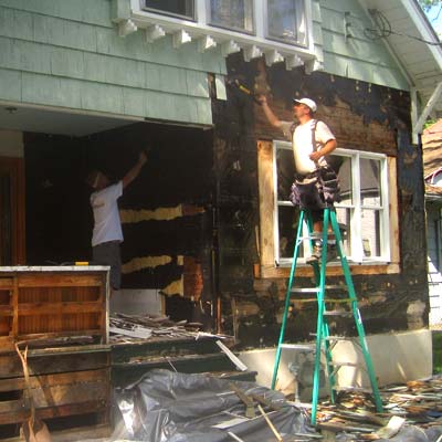 Tearing off old siding shingles.