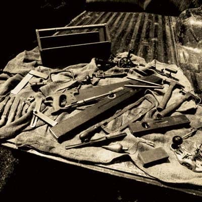 A collection of a variety of vintage tools laid out on a tarp in the back of a truck.