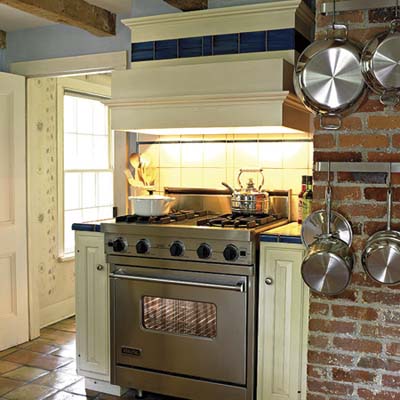 A kitchen with a large oven and metal pots hanging on the wall