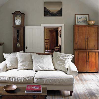 A couch in front of a grandfather clock in a living room