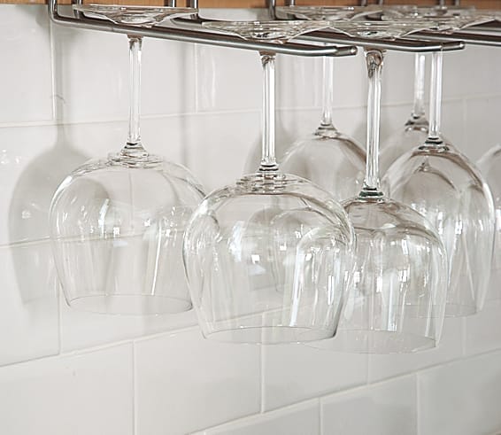 wine glasses that are hung above a countertop