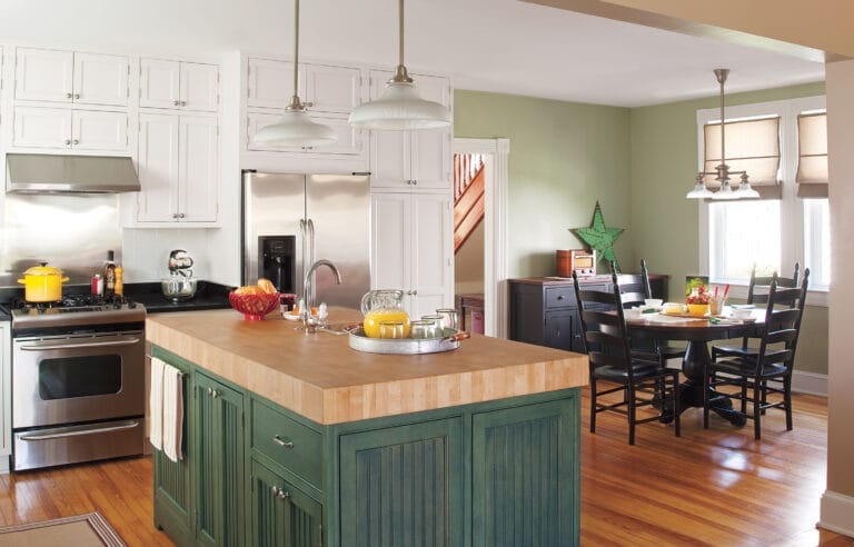 a bright kitchen with green painted walls and an island and kitchen items placed in cabinets