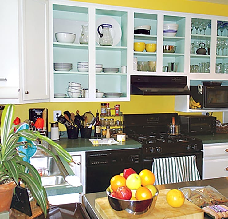 a crowded kitchen with lots of dishes in the cabinets and items on the counter