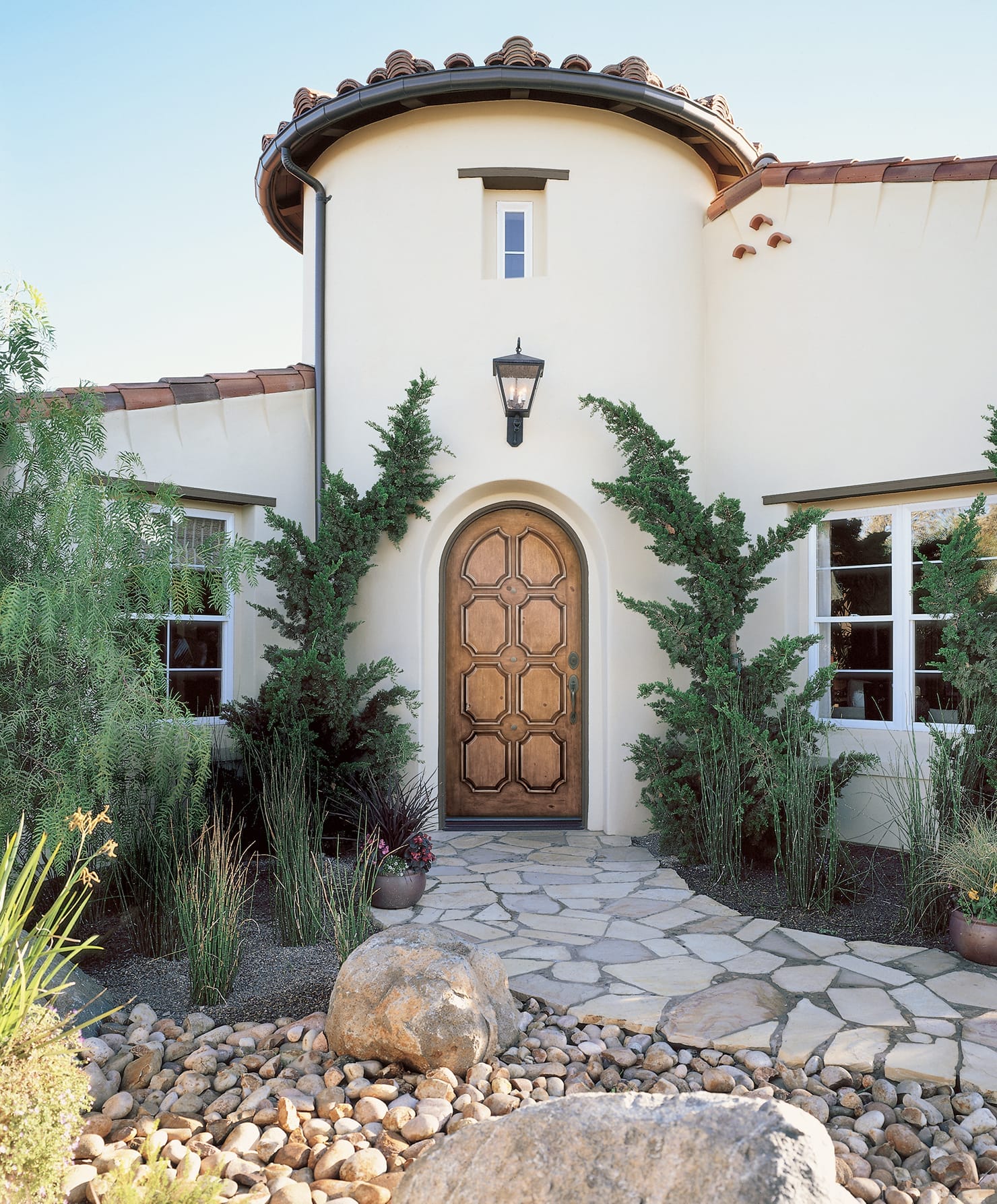 A Mediterranean-style stucco home features an arched fiberglass front door with intricate paneling.