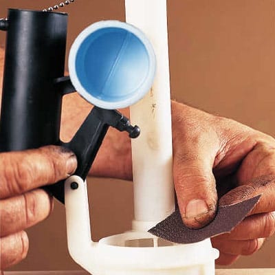 A person sands the toilet flapper valve seat.