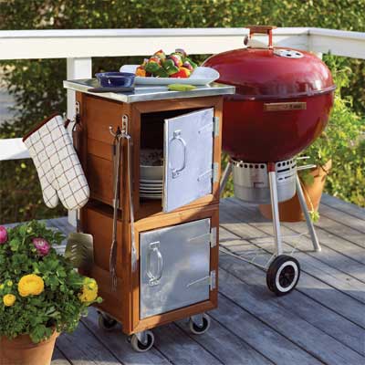 Grilling station with a small grill and kitchen utility rolling cabinet.