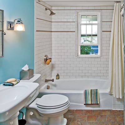 Clean white bathroom with cast-iron tub, ceramic tile floors, and classic pedestal sink.