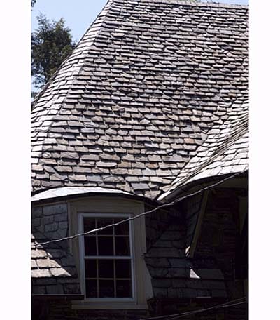 Slate-covered curved roof resembling traditional thatch construction.