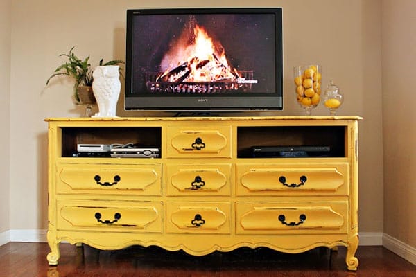 A media center made of a yellow vintage dresser.