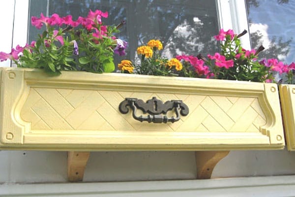 Yellow window box filled with flowers made of a dresser drawer.