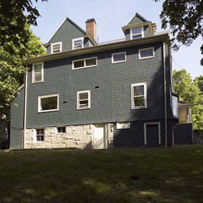 Sloping backyard before renovation with house and existing landscaping.