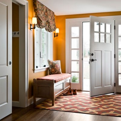 Entryway with new wood floors, door flanked by windows, and built-in coatroom.