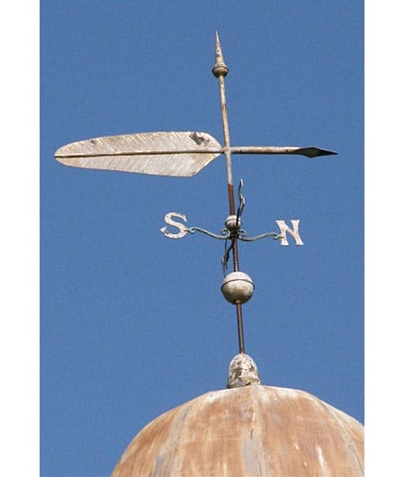 A worn weathervane in the shape of a quill.