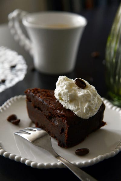 A chocolate desert on a plate next to a mug.