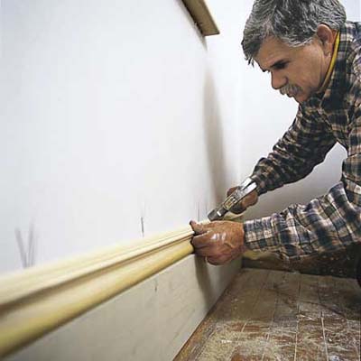 Man adding baseboards to room