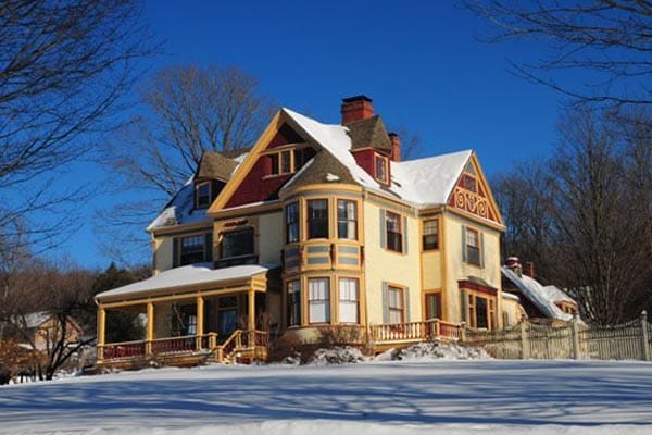 A large house with snow on the roof in Vermont