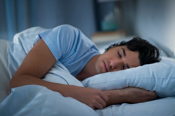 Person sleeping peacefully in a dark bedroom.