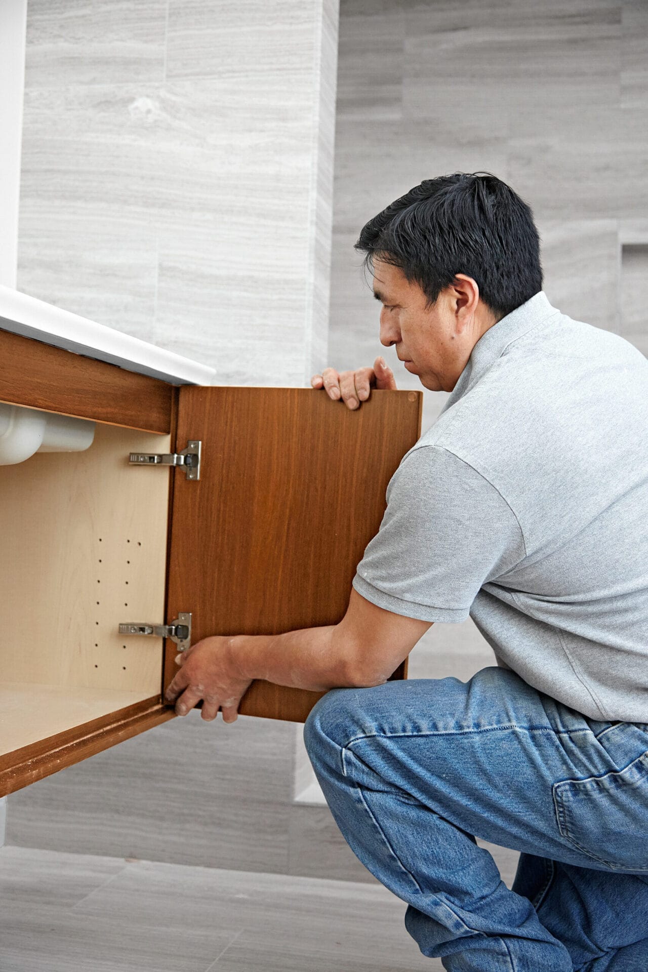 A man adds doors to the wall-mount vanity.