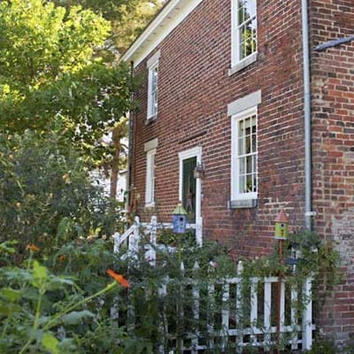 A lively garden with a white fence beside a brick house