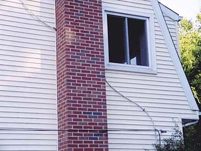 Main electrical cable running directly through brick chimney structure.