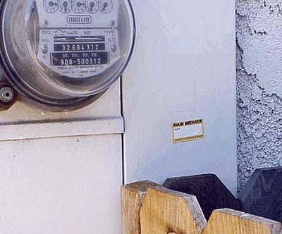 Electrical main breaker panel blocked by wooden post obstruction.