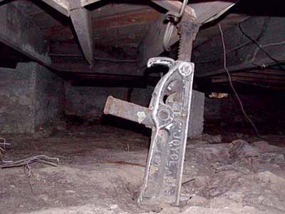 Car jack used as structural support beam in home crawlspace.