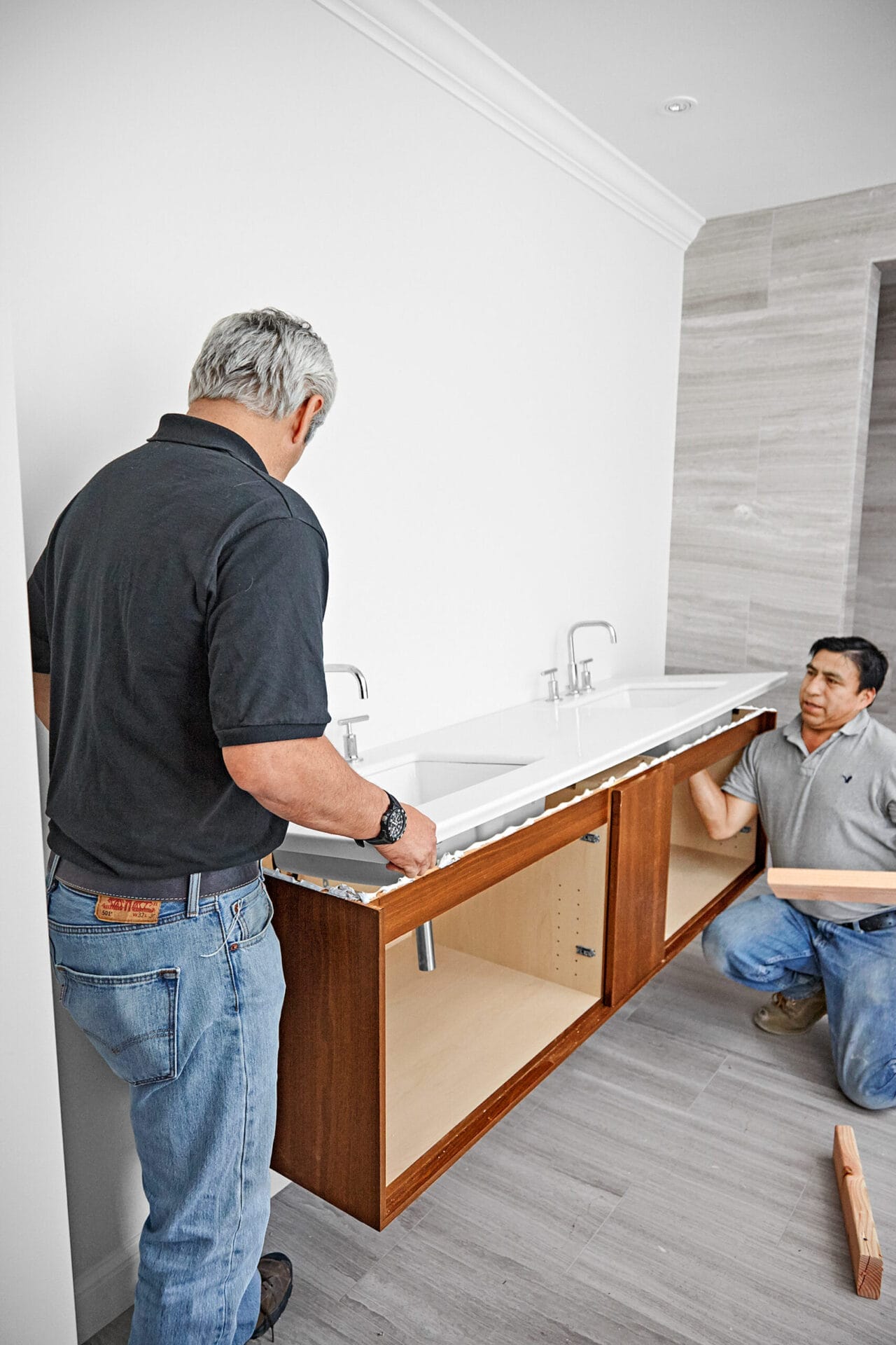 Two men remove spacers from the wall-mount vanity and sink.