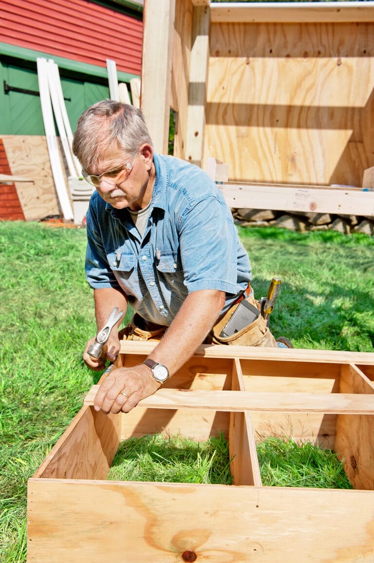 Tom Silva hammers together the chicken coop frame.