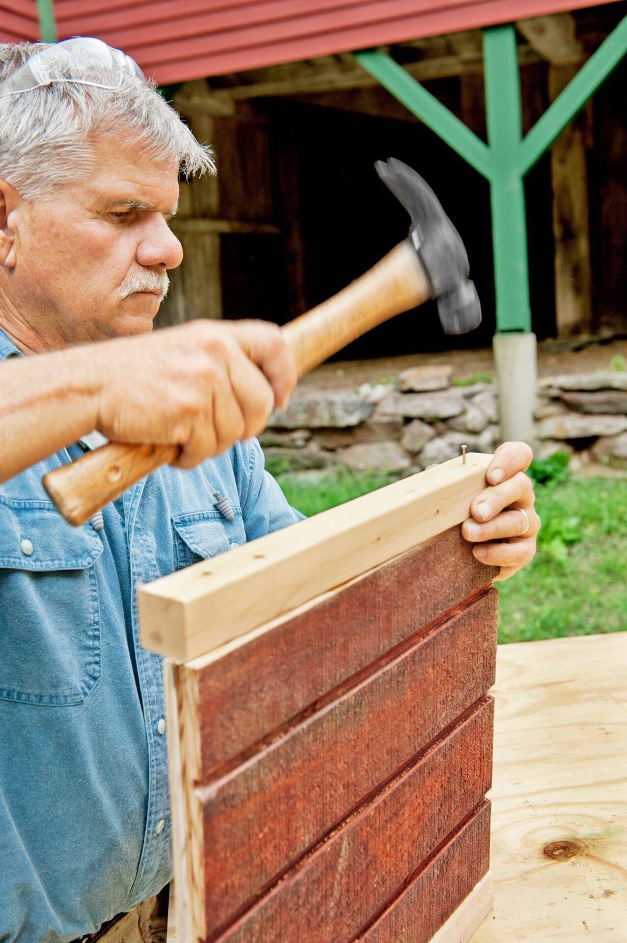 Tom Silva uses a hammer to built the chicken coop door.