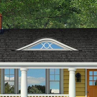 Curved eyebrow dormer and white columns creating prominent entry focal point.