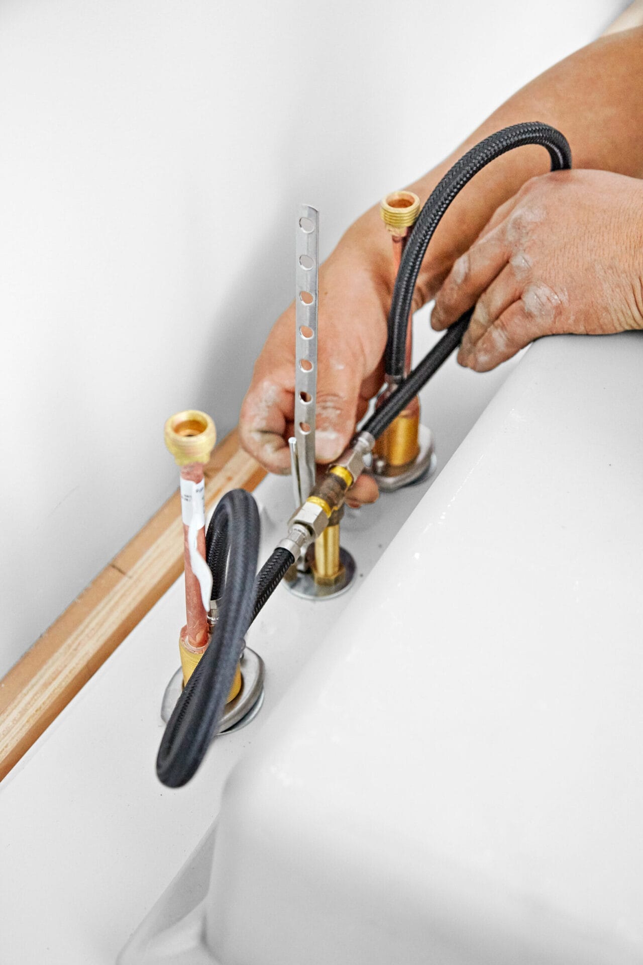 A person adds supply lines to the wall-mount vanity and sink.