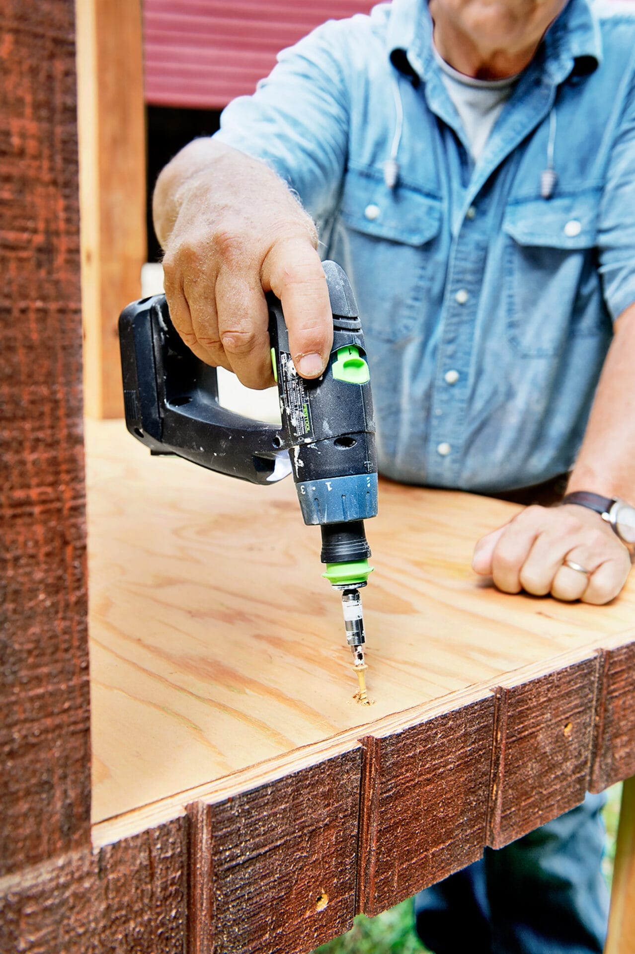 A drill is used to attach the floor of the chicken coop.