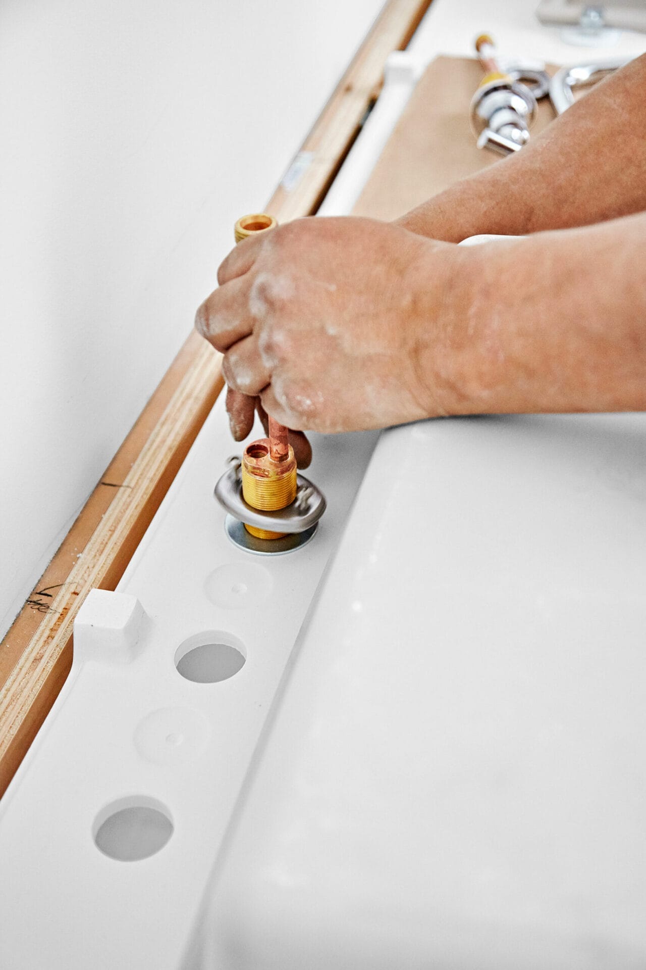 A man installs handles to the wall-mount vanity and sink.