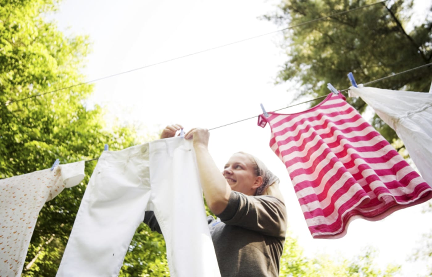 A woman clipping clothes onto a clothesline.