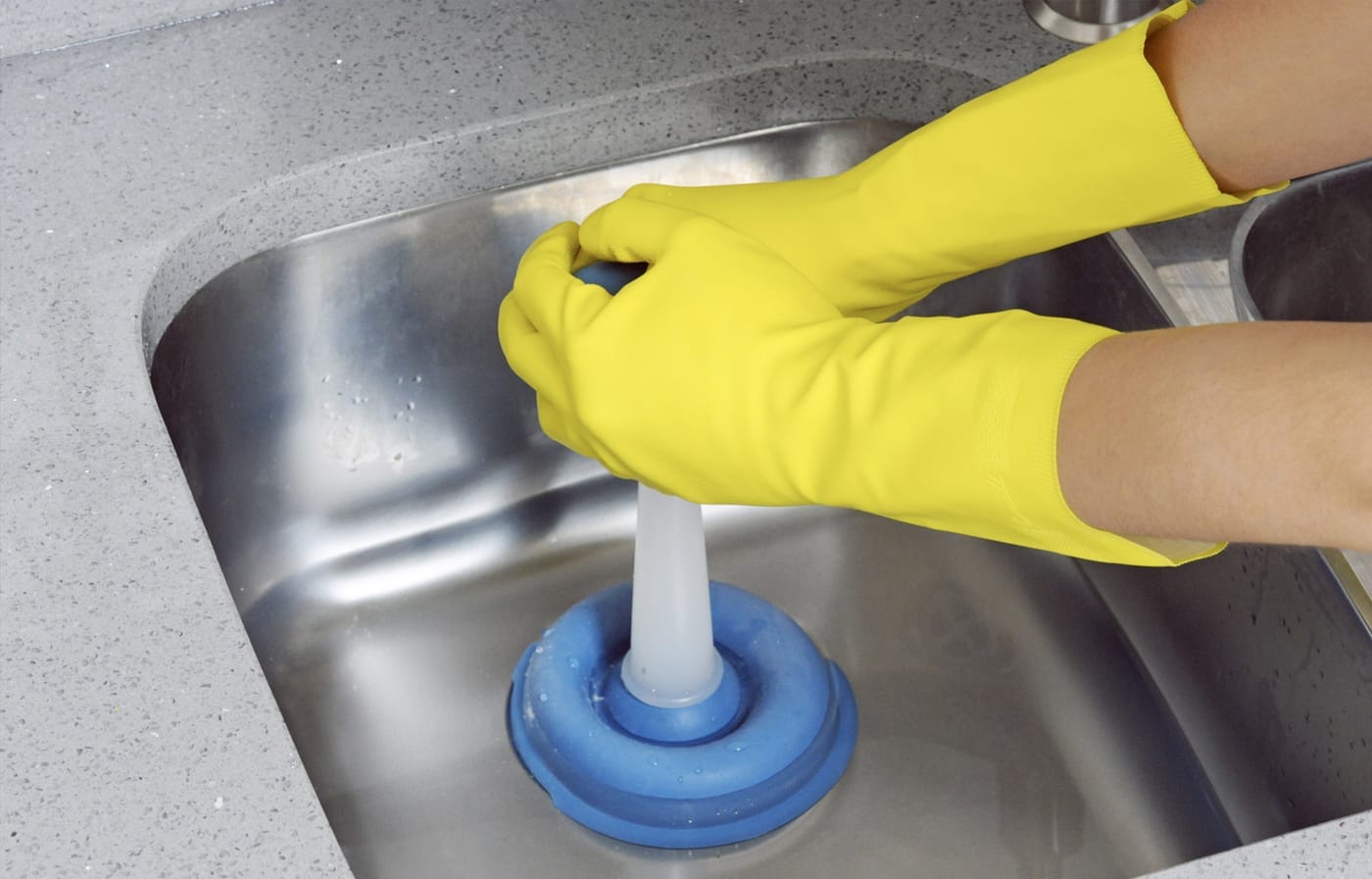 A person using a plunger to unclog a sink drain.