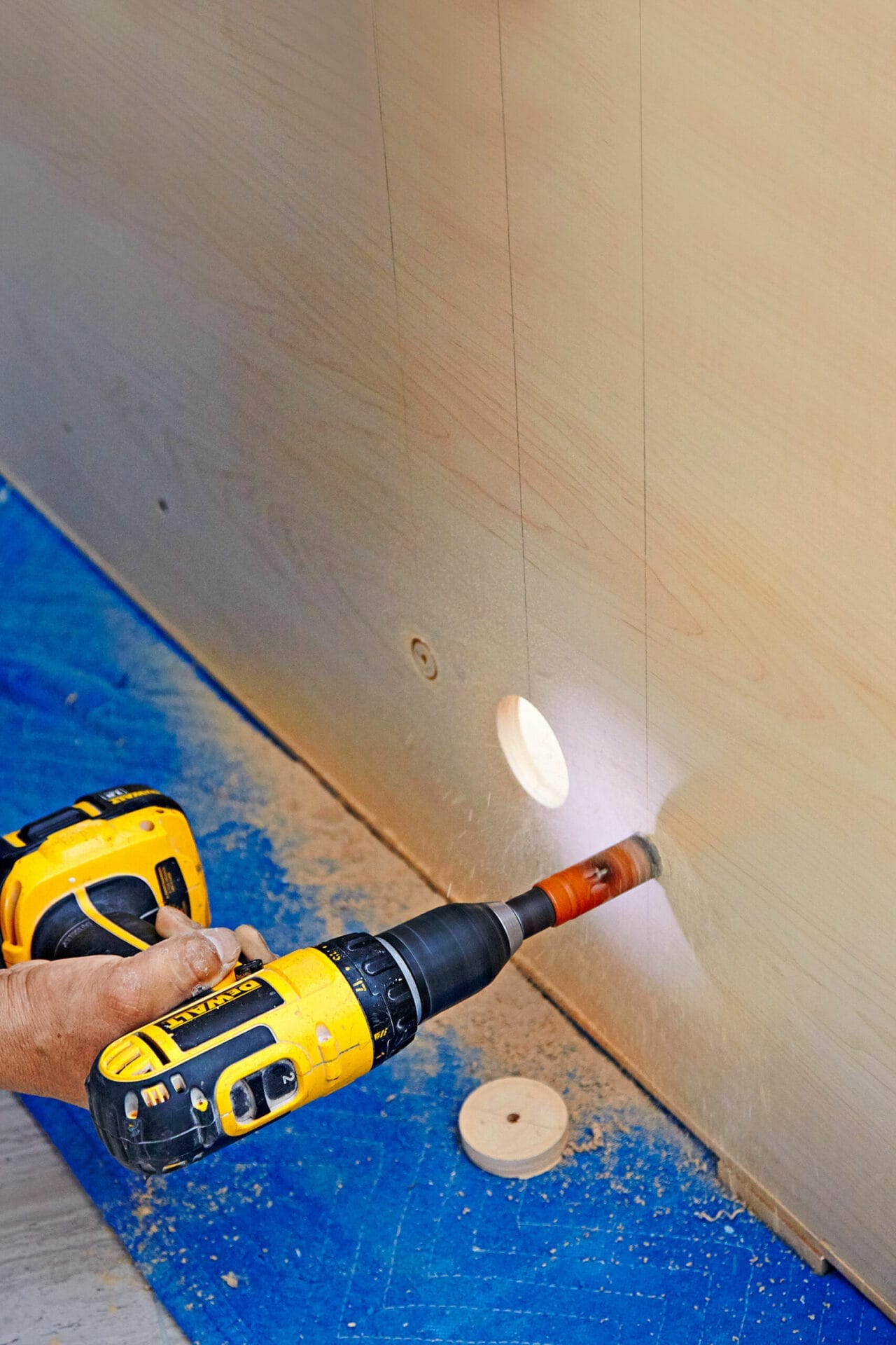 A person cuts plumbing holes for wall-mount vanity and sink.