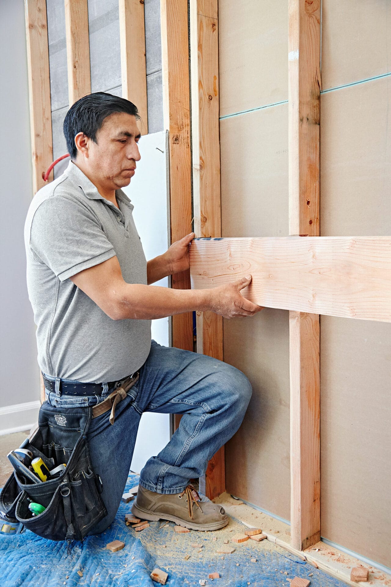 A man attaches the wall-mount vanity and sink bracing.