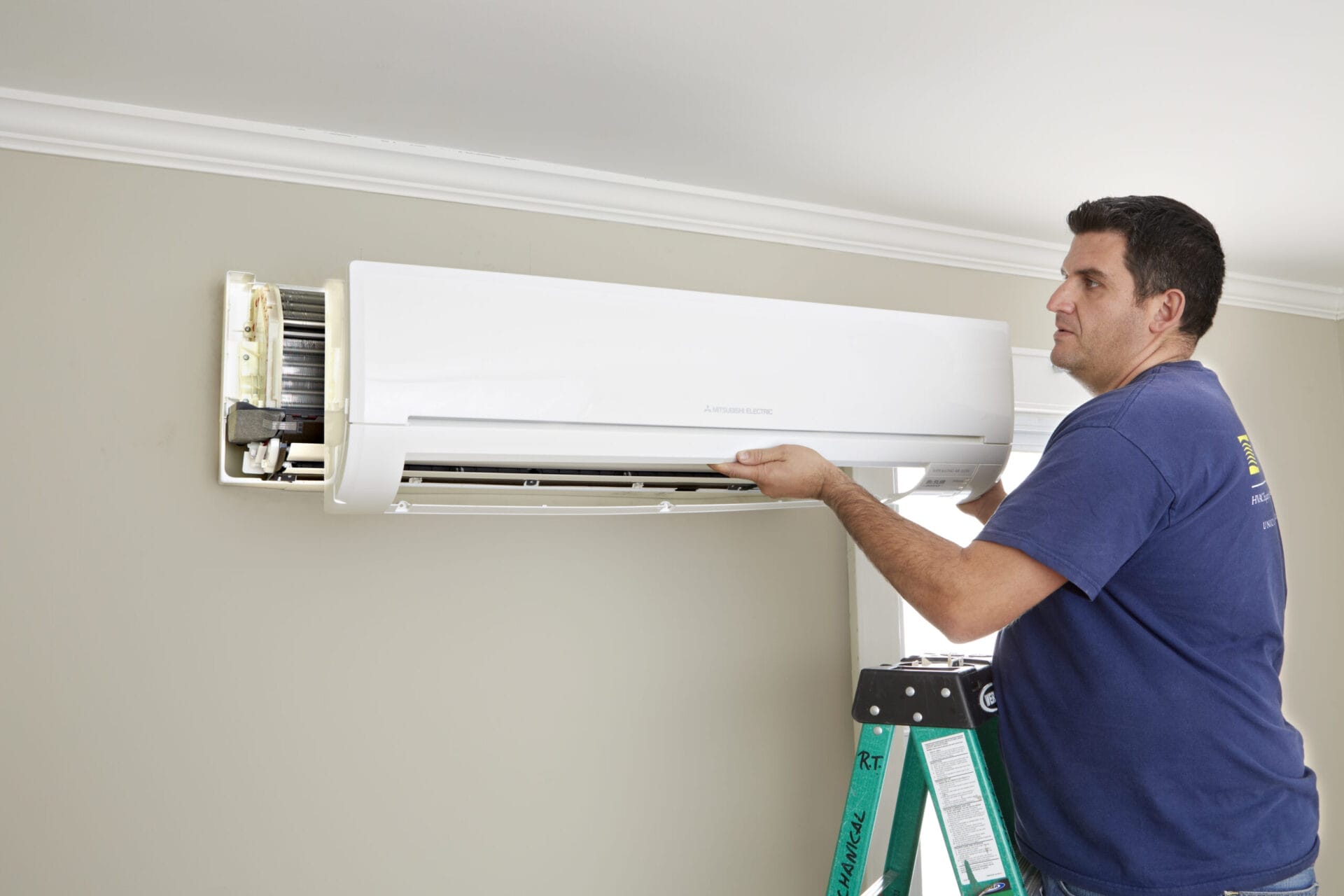 A main affixing a cover to an AC unit mounted on a wall.