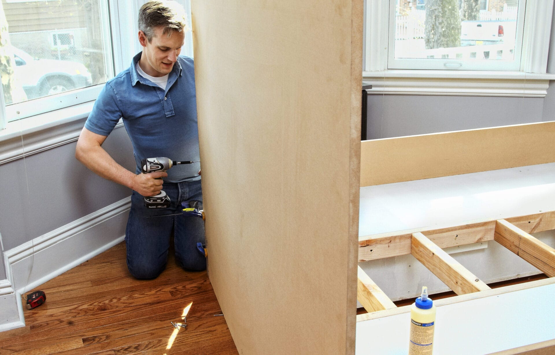 A man drills a headboard on a storage bed.