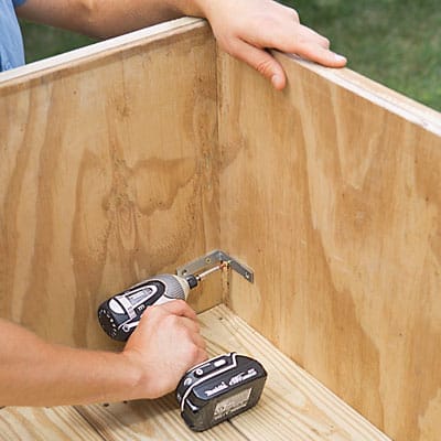 Metal brackets are drilled into the lily pond box corners to reinforce them.