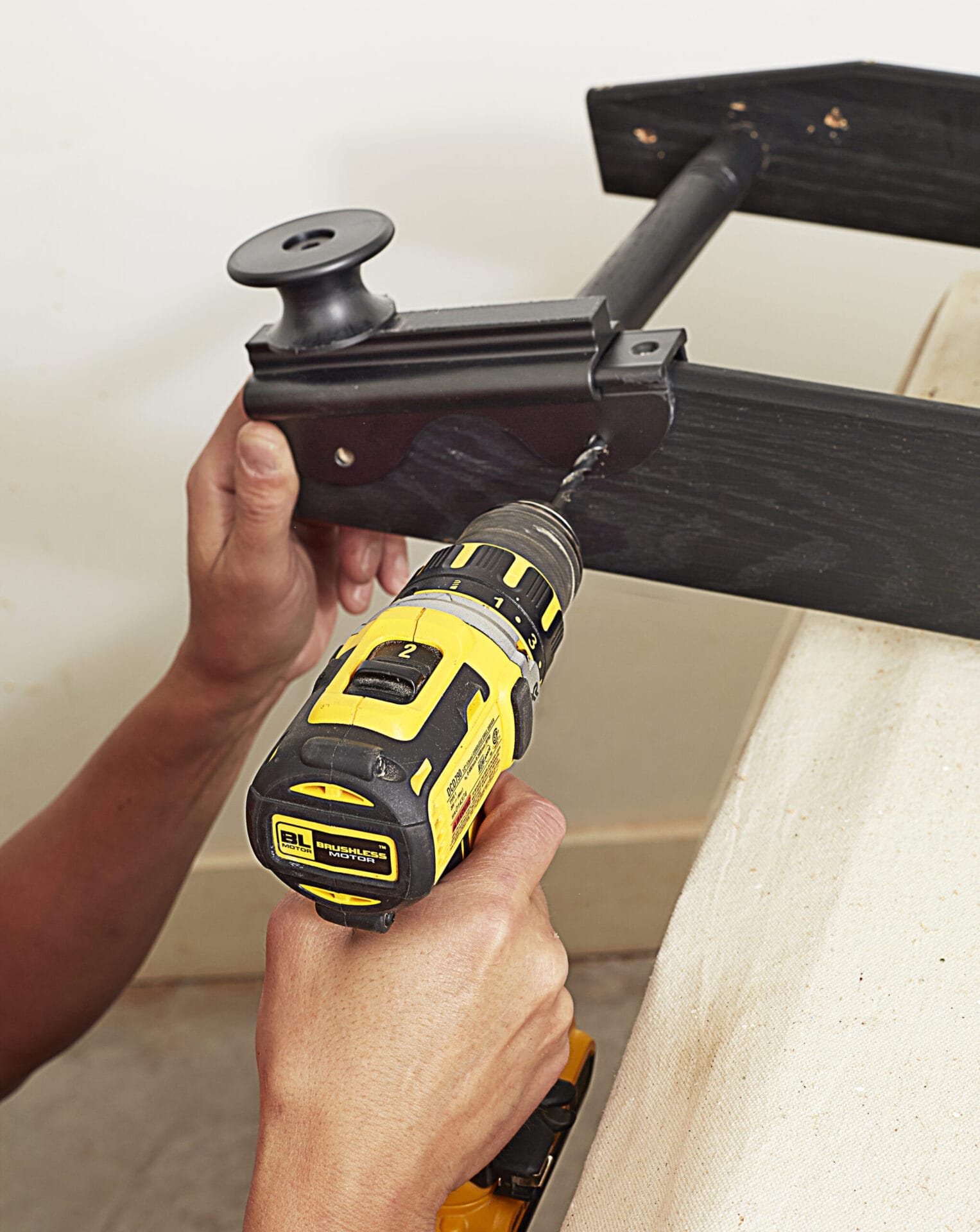 Image of a person completing a step in the DIY rolling library ladder project, which involves attaching the rollers
