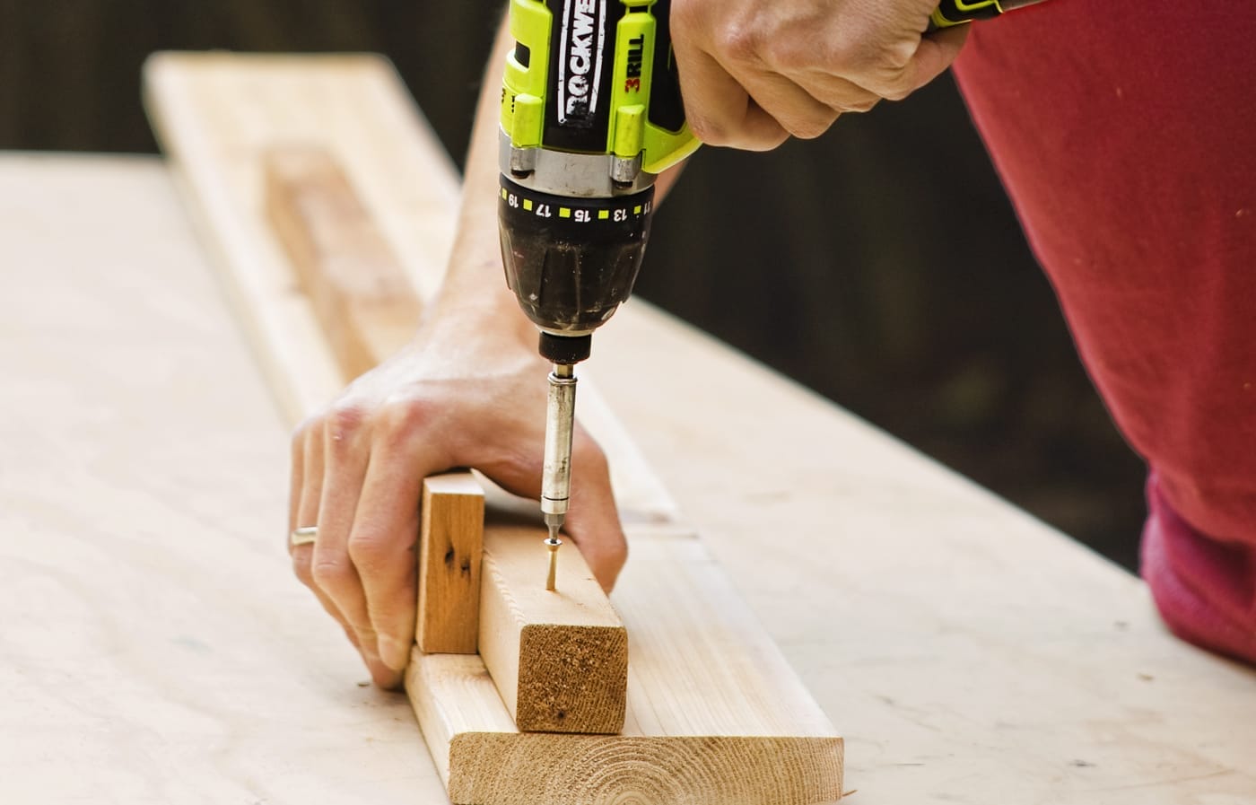 A person drills wood pieces together to start the trellis frame for the privacy planter.