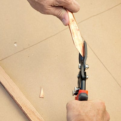 Tin snips cutting V-shaped point into copper leg bottom.