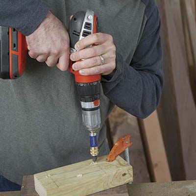 A person predrills screw holes to build a table.