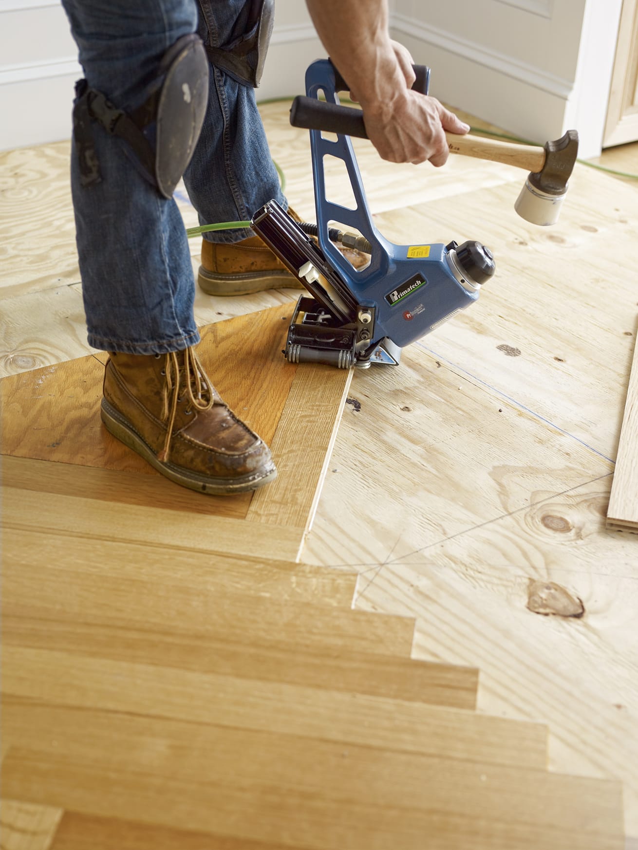 Hammering down herringbone wood flooring.