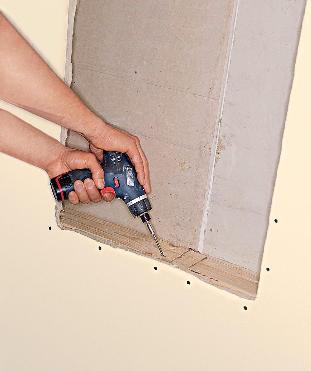 using a drill to install the blocking for a medicine cabinet installation