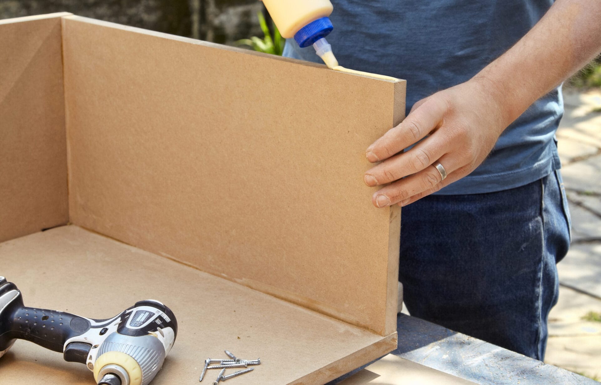 A person glues together MDF pieces to build a storage bed.