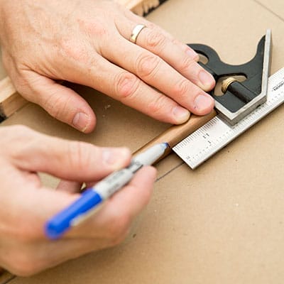 Hands marking copper tubing with combination square and marker.