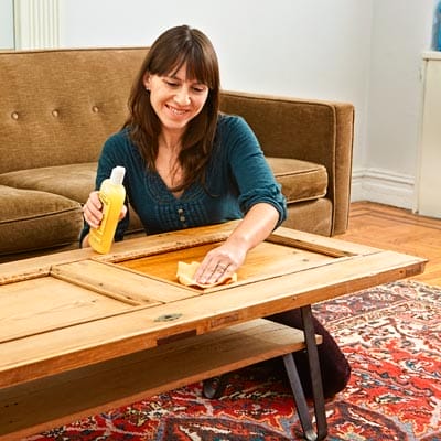 A woman seals her salvaged cabinet door coffee table.
